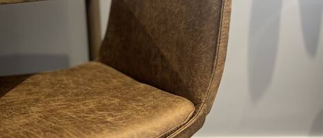A close-up of a brown upholstered chair with a wooden table leg and a dark metal frame.