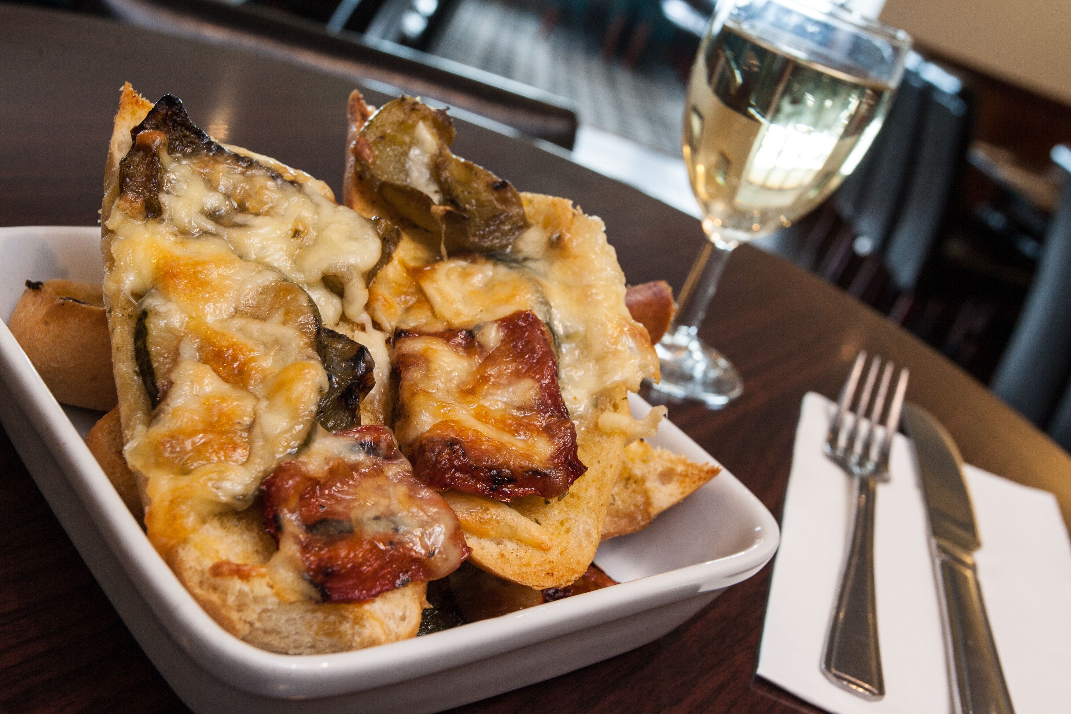 A dish of food with a glass of white wine on a table.