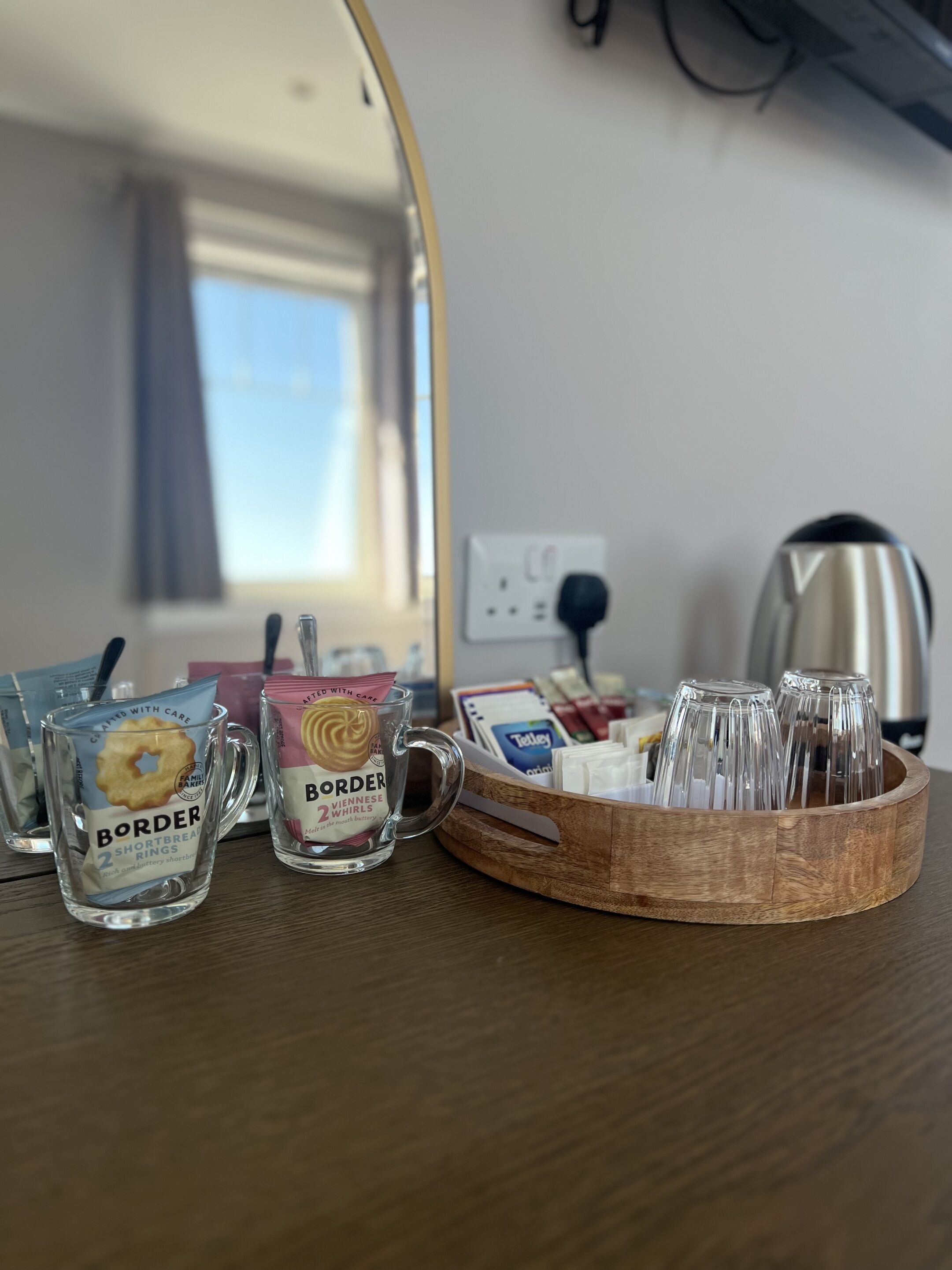 Una bandeja de madera con dos tazas de vidrio, una etiquetada 'Border Shortbread Rings' y la otra 'Viennese Whirls'.
