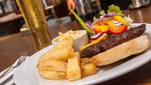 Une assiette avec une saucisse, des frites et une salade.