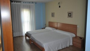 Une chambre avec deux lits, une tête de lit en bois, une table de chevet et une armoire.