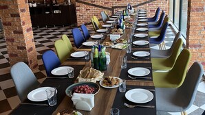 Une longue table à manger, entourée de nombreuses chaises, avec des assiettes, des verres et divers plats.