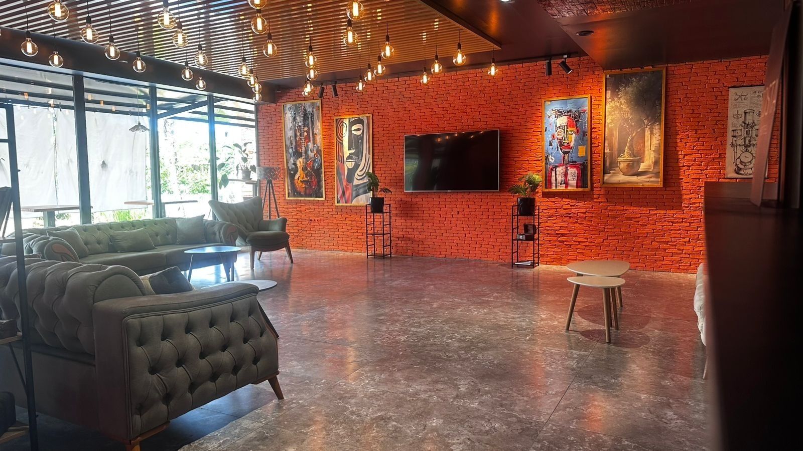 A spacious room with a brick wall, a large flat-screen TV, and a sofa.
