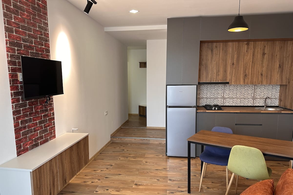 A modern kitchen with a built-in refrigerator, a wooden countertop, and a patterned backsplash.