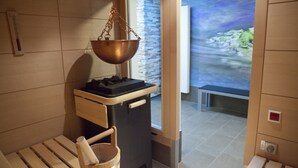A sauna room with a wooden bench, a wooden bucket, and a copper basin. - Hotel Alexa (Bad Mergentheim)
