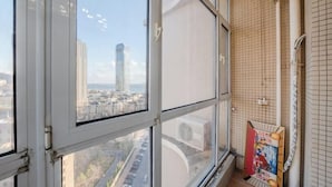 Una habitación con ventanas amplias que ofrecen vistas a un paisaje urbano, incluyendo un edificio alto.
