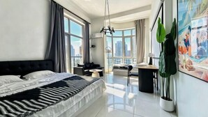 Una habitación de hotel moderna con una cama grande, un comedor y vistas a la ciudad.