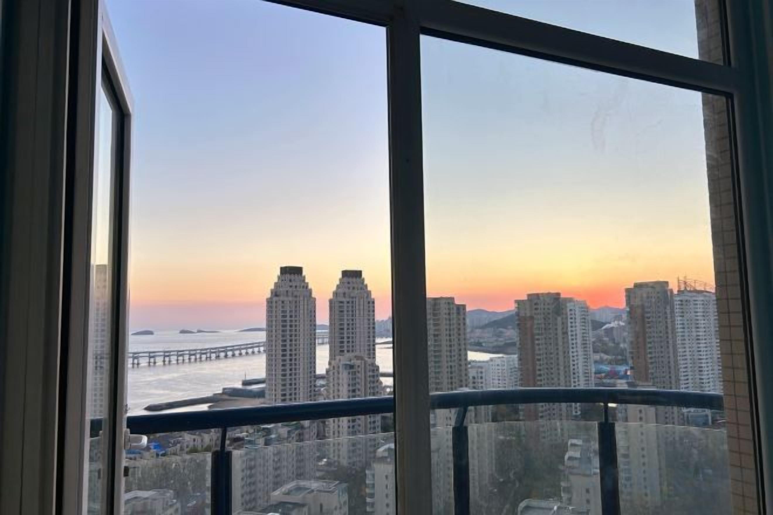A high-rise building with a view of a sunset and a bridge in the distance.
