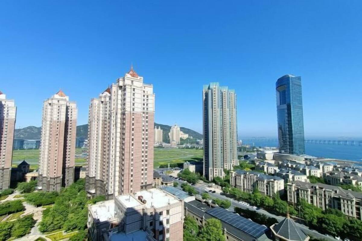 Un paysage urbain avec de nombreux immeubles de grande hauteur, dont un gratte-ciel moderne remarquable, et une vue sur la côte.