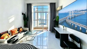 Una sala de estar moderna con una mesa de vidrio, un sofá con cojines coloridos, una gran pantalla de televisión y vistas a un puente sobre el agua.
