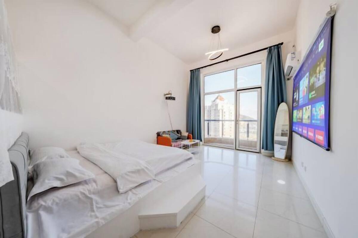 Une chambre moderne avec un lit, un bureau et une grande fenêtre.