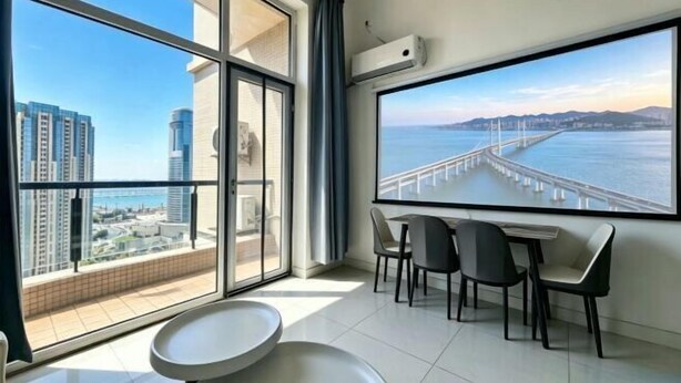 Una habitación moderna con un ventanal grande, una mesa de comedor con sillas y un equipo de aire acondicionado.