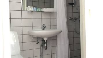Un baño con lavamanos blanco, inodoro y zona de ducha.