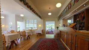A dining area with tables and chairs, a wooden floor, and a red carpet. - Ølsted Kro (Olsted)