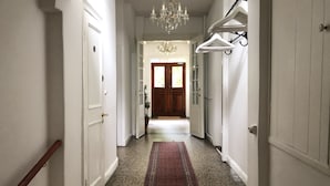 A hallway with white walls, a red carpet, and a chandelier. - Ølsted Kro (Olsted)
