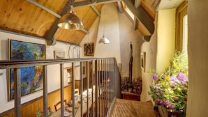 A wooden interior with a staircase, paintings, and a flower arrangement. - La Grange de Coatelan (Plougonven)