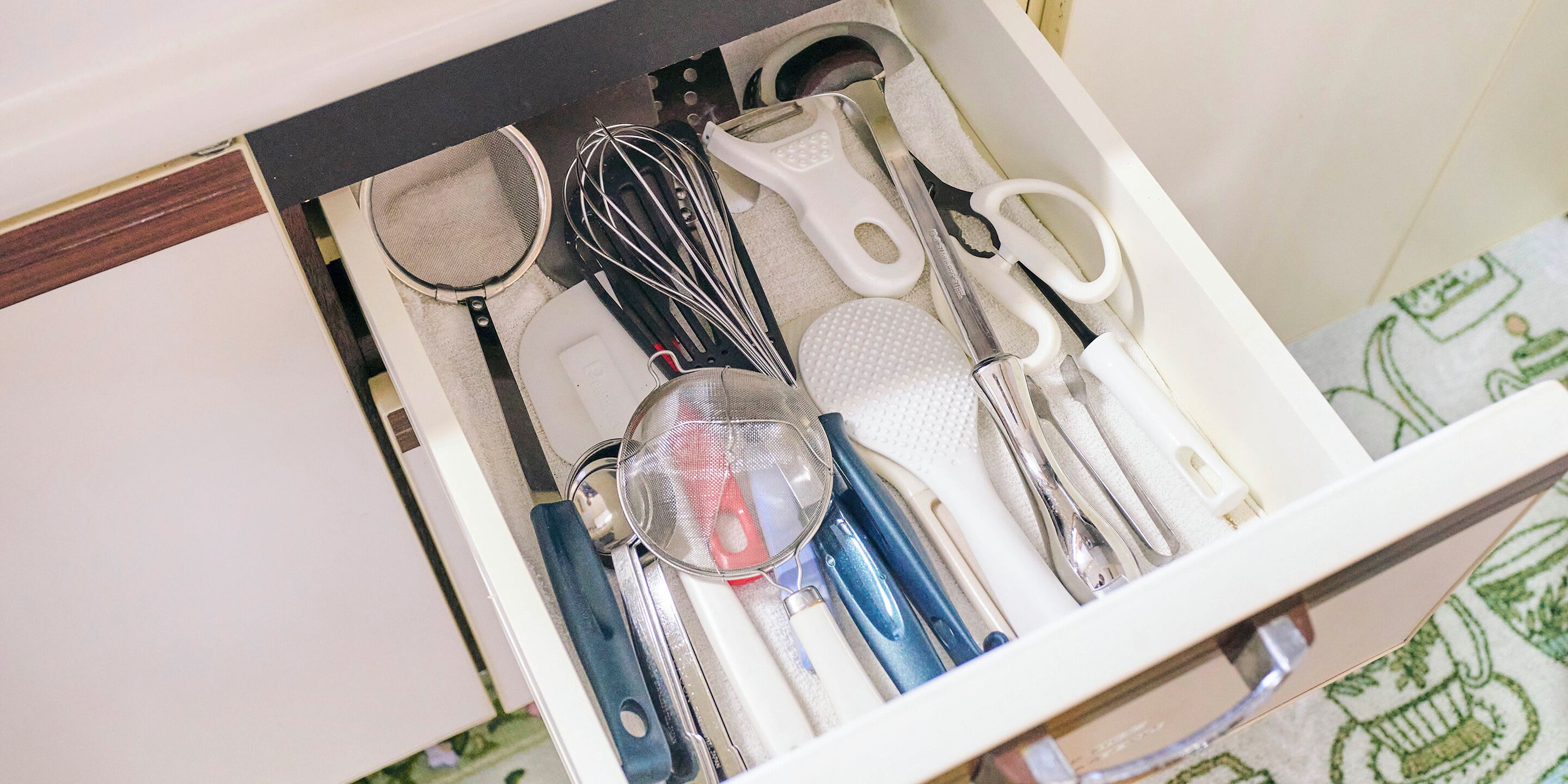 Un tiroir contenant des ustensiles de cuisine, notamment un fouet, une spatule et une passoire.