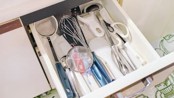 Un tiroir contenant des ustensiles de cuisine, notamment un fouet, une spatule et une passoire.