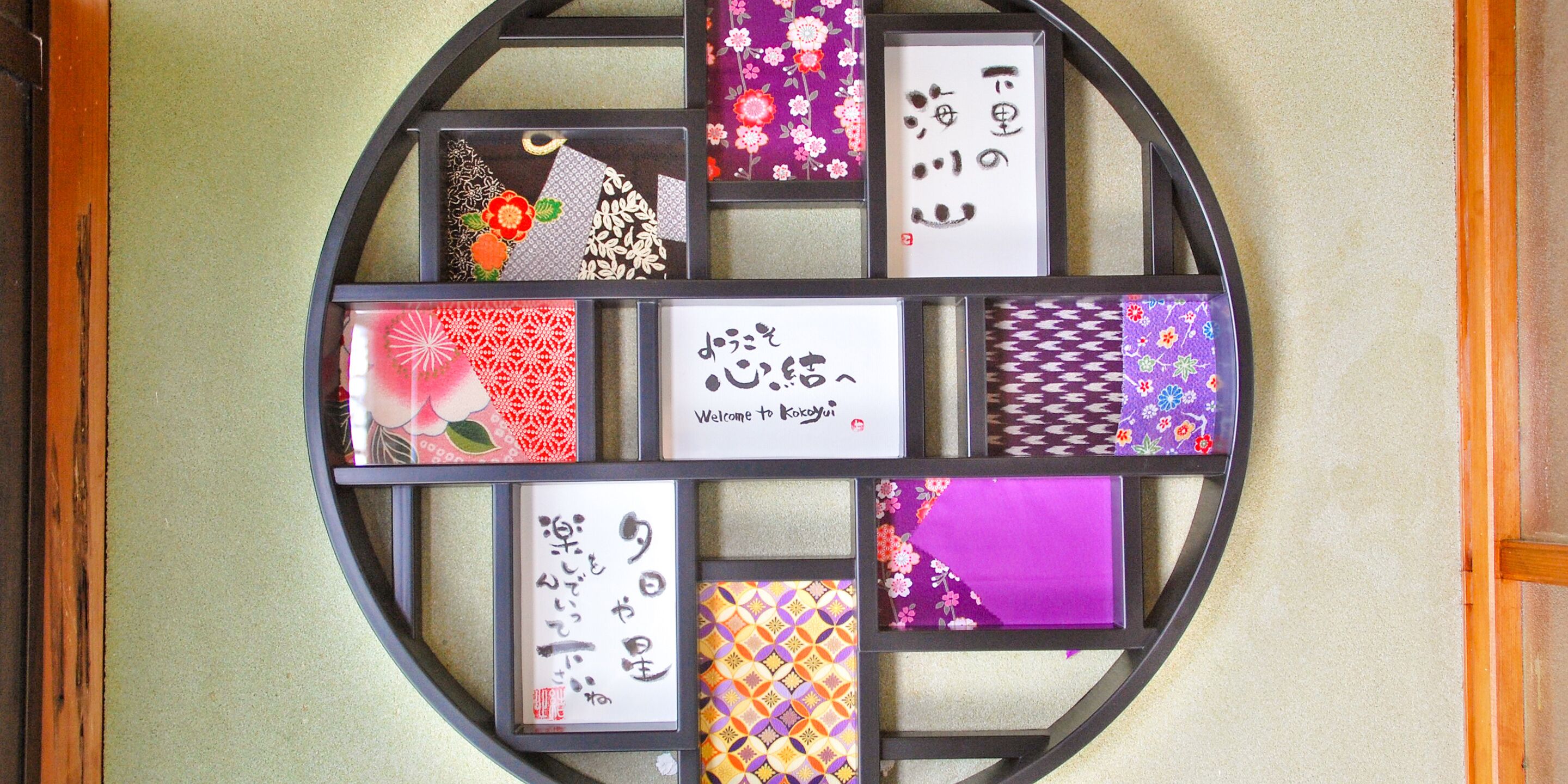 A wall with a circular arrangement of framed Japanese calligraphy and artwork.
