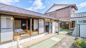 A traditional Japanese house with tatami mat flooring, sliding doors, and a garden area with plants and a small pond. - Kokoyui Guesthouse (Nachikatsuura)