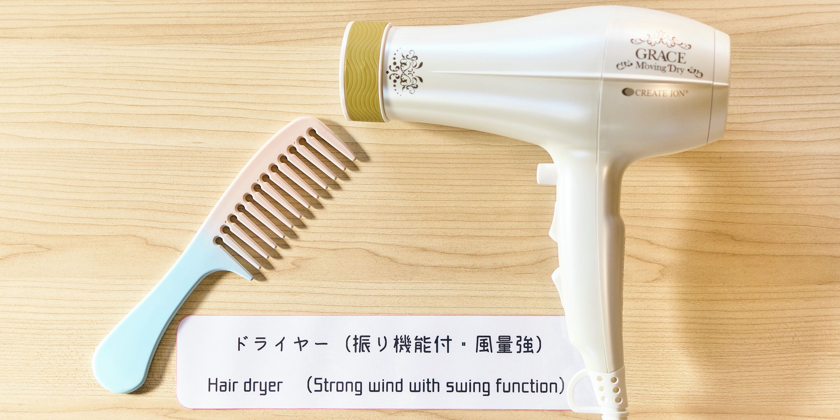 A hair dryer and comb on a wooden surface.