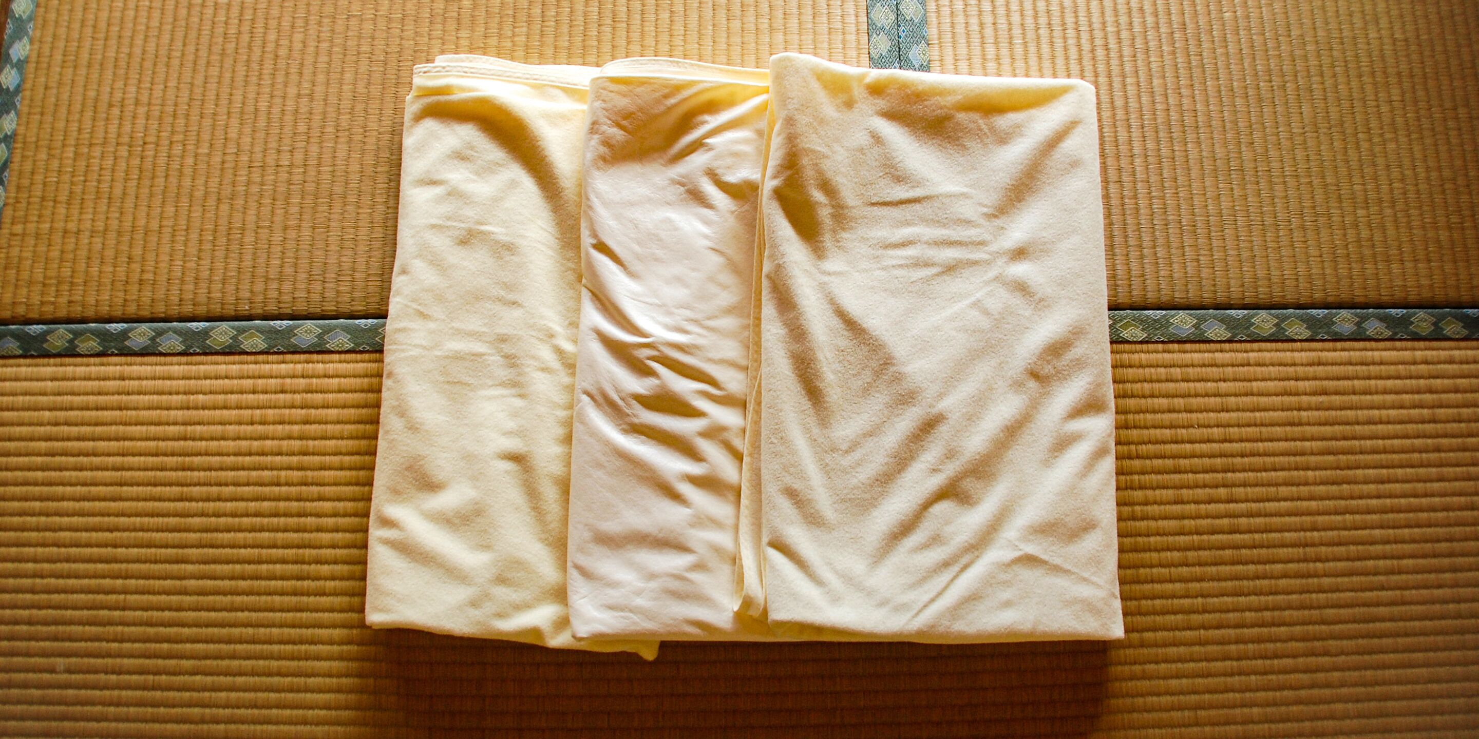 A neatly folded beige towel on a textured brown mat, likely in a hotel room.