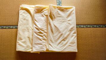 A neatly folded beige towel on a textured brown mat, likely in a hotel room.