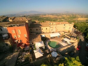 A courtyard with a swimming pool, outdoor seating, and a view of the surrounding landscape. - Residence Borgo da Mare (Monteprandone)