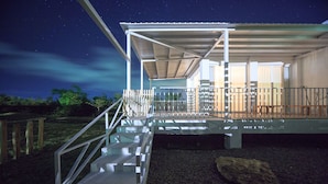 A modern building with a covered outdoor area, a staircase leading to a deck, and a view of the night sky. - Wild Island B&B (Hengchun)