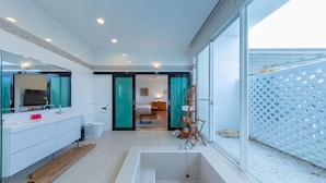 A modern bathroom with a large bathtub, a vanity with a mirror, and a shower area. - Wild Island B&B (Hengchun)