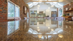 A spacious kitchen with modern appliances, a large island, and a brick wall. - Wild Island B&B (Hengchun)