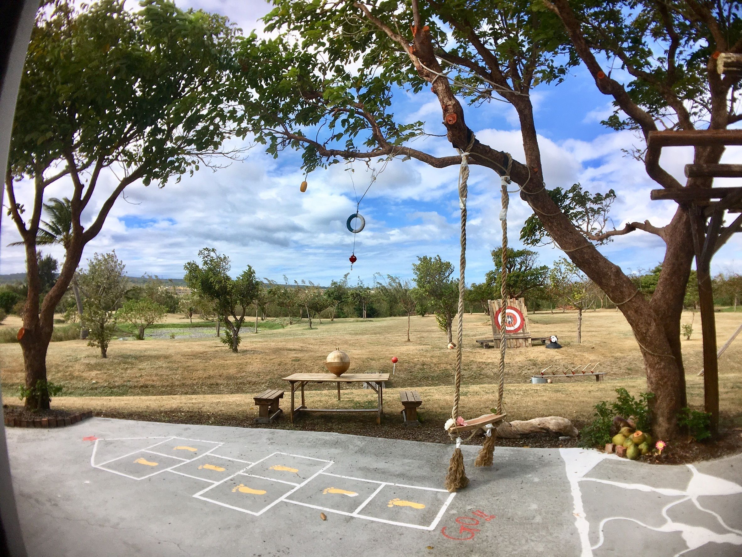 A park with swings, a picnic table, and a target in the background.