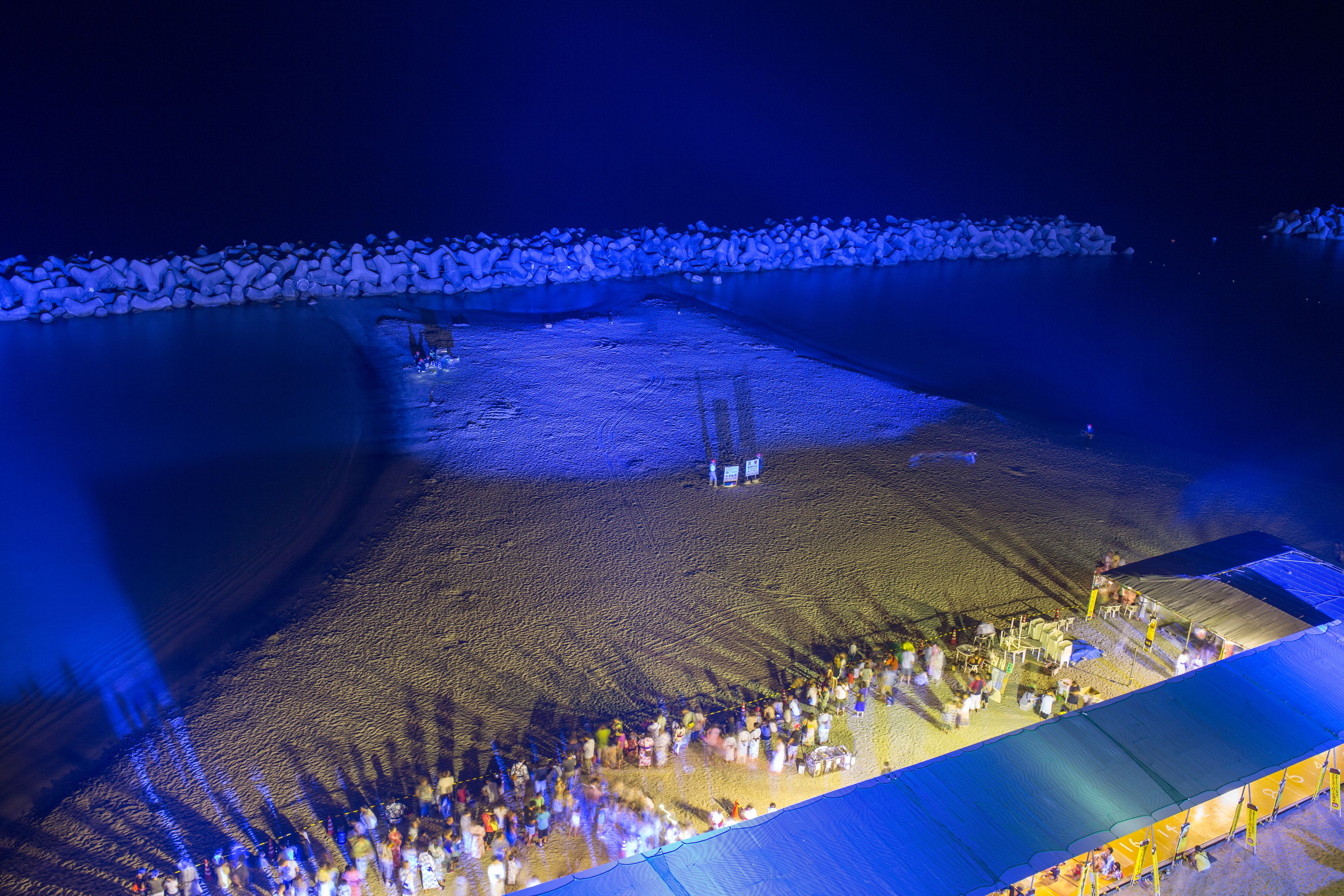 Une vue aérienne d’une plage où une foule s’est rassemblée sous une grande tente.