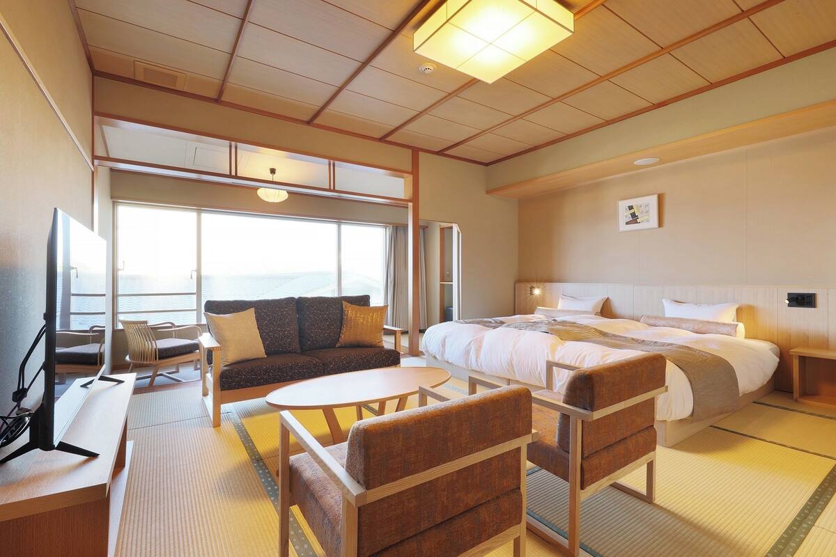 Quarto de hotel com uma cama grande, um sofá, uma mesa de jantar e uma televisão.