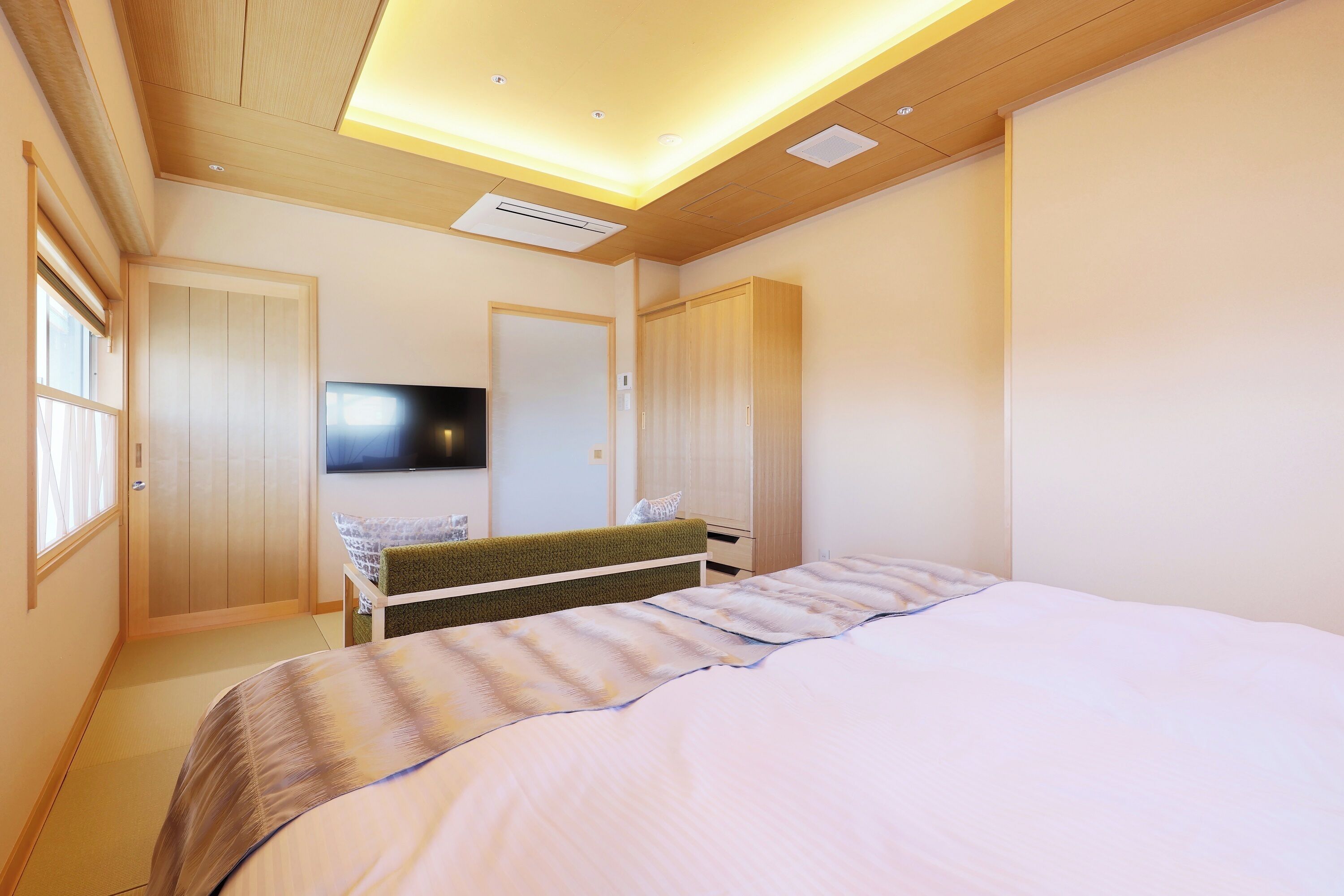 A modern bedroom with a bed, a TV, and a wardrobe.
