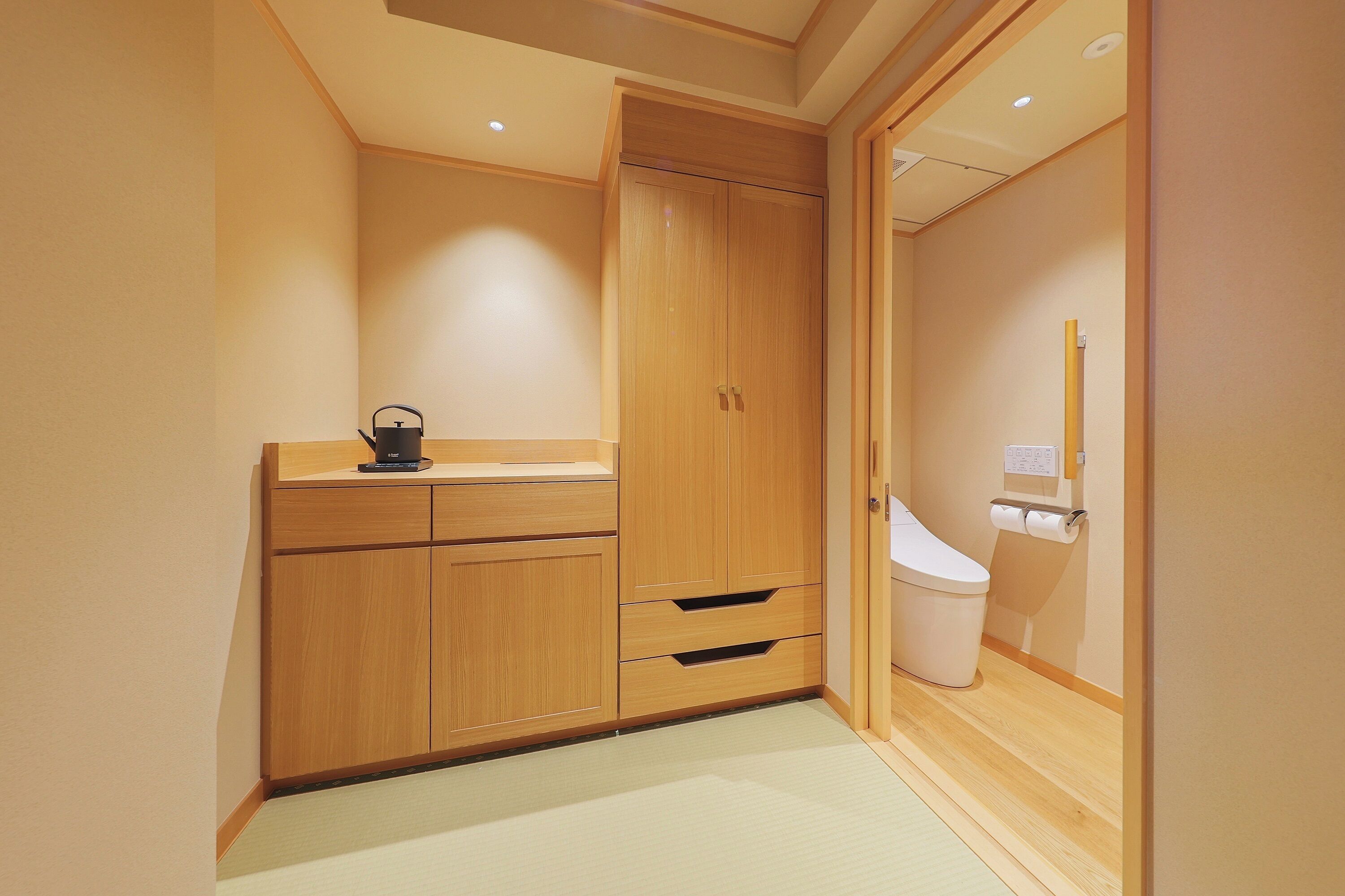 A compact bathroom with wooden cabinetry, a toilet, and a small sink area.