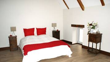 A bedroom with a bed, two bedside tables, a nightstand, a wooden bench, and a window.