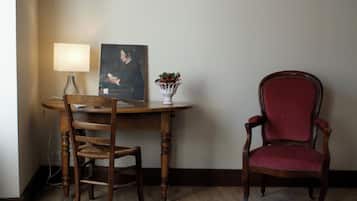 Una mesa de madera para comer con una silla, una lámpara, un retrato enmarco y un florero con flores.