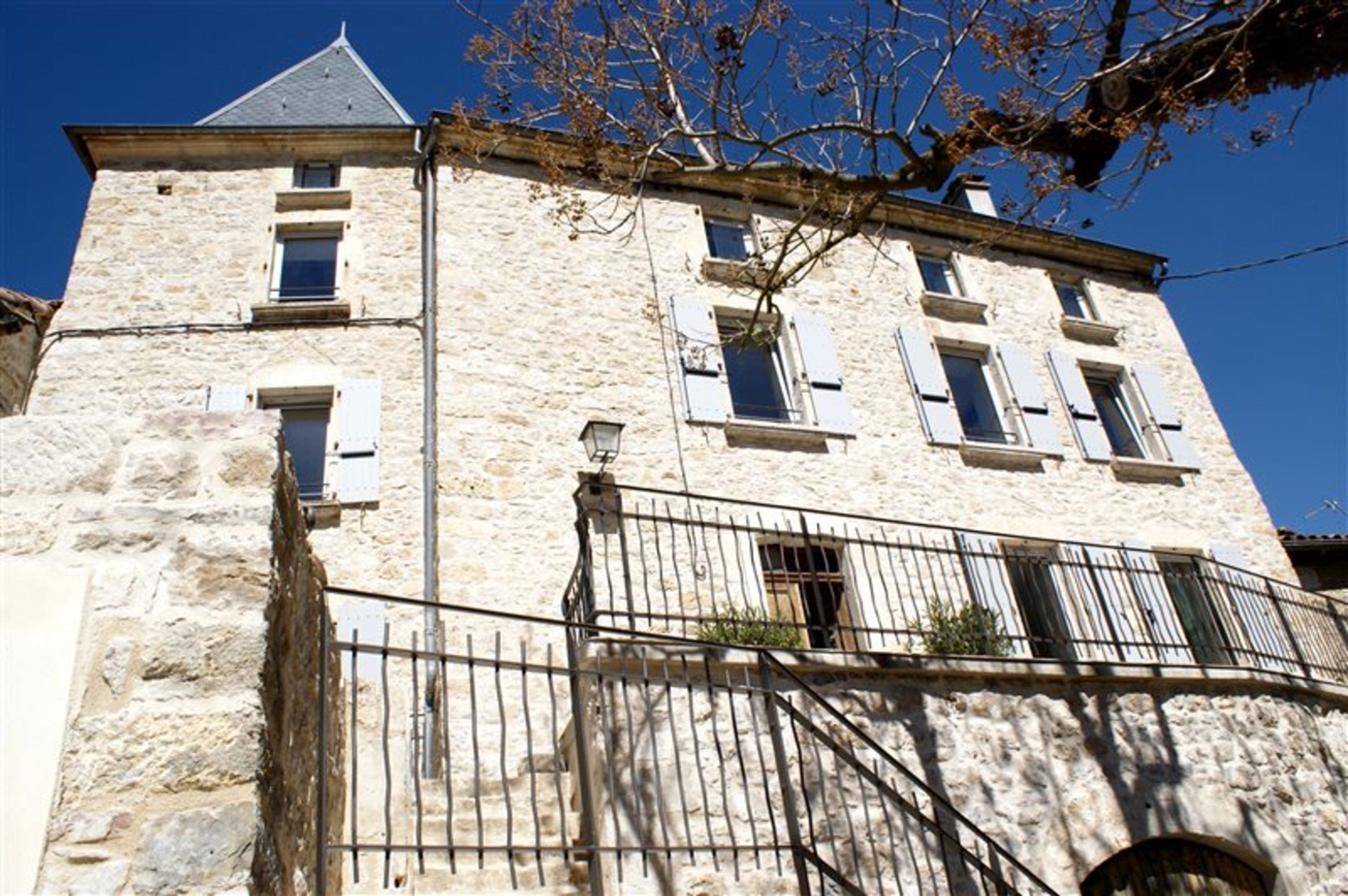 Ein Steinhaus mit Balkon und Metallzaun.