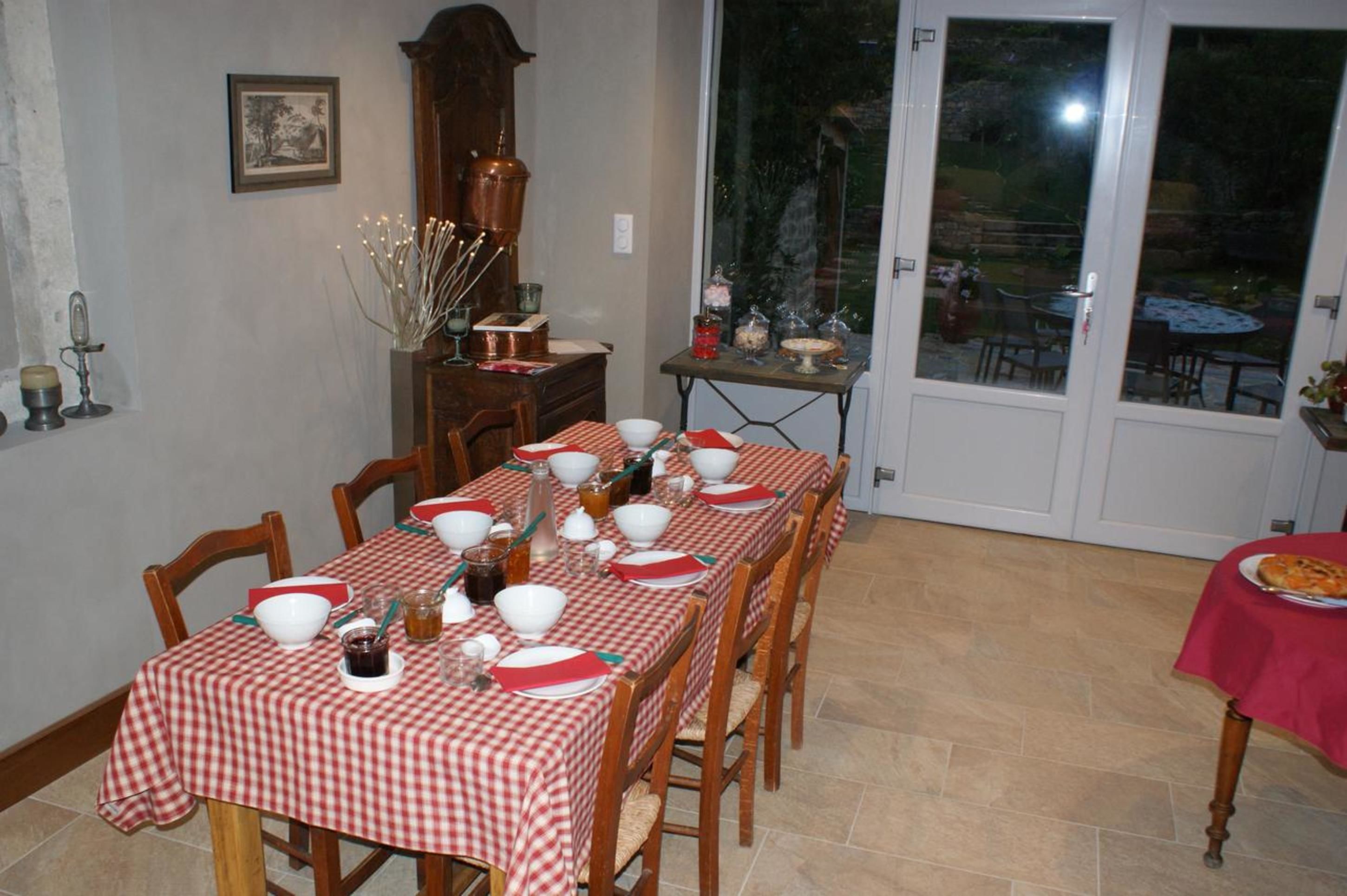 A dining area with a checkered tablecloth, wooden chairs, and a dining table set for a meal.