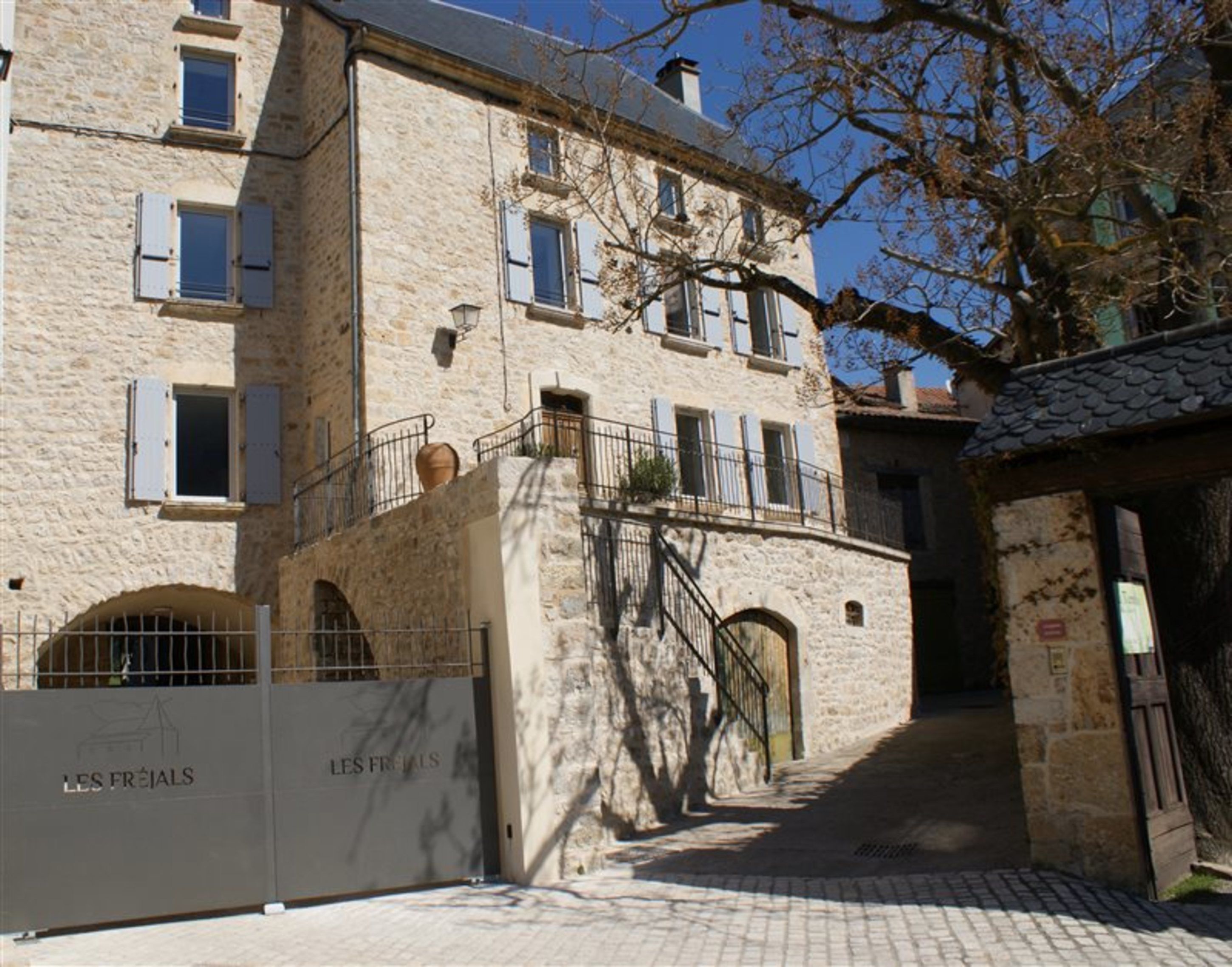 A stone building with multiple windows and a gated entrance.
