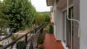 Un balcon doté d’un sol carrelé, de plantes en pot et d’une rambarde en métal.