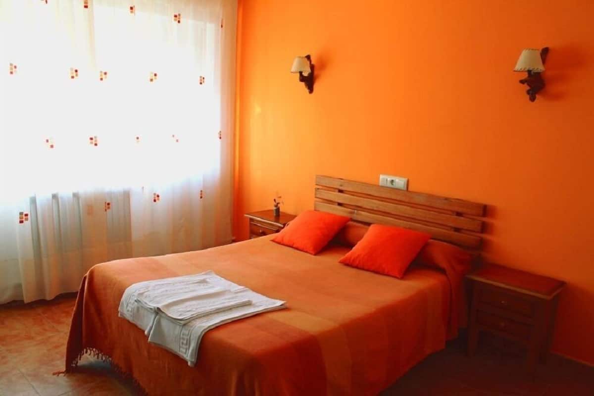 A room with a bed, two nightstands, and a window with curtains.