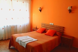 Een kamer met een bed, twee nachtkastjes en een raam met gordijnen.