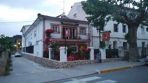 Un edificio con un letrero que dice "Hostal Rio Mundo". Tiene un balcón con flores rojas y una base de piedra.
