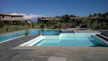 En säsongsöppen utomhuspool, parasoller och solstolar