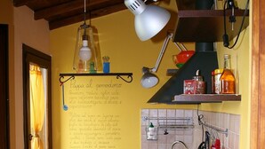 A kitchen with wooden cabinets, a sink, and a chalkboard with handwritten notes. - Vento di Maremma (Grosseto)