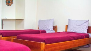 A room with three wooden beds, each with a purple bedspread and a matching pillow. - Savage Wilderness - Hostel (Sagana)