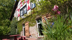 A traditional half-timbered building with a stone wall, a wooden door, and a red bench area. - Rittergut Haus Laer (Bochum - Laer)