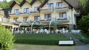 A multi-story hotel with balconies, outdoor seating, and a staircase leading to the entrance. - Moselhotel Restaurant Peifer (Brodenbach)